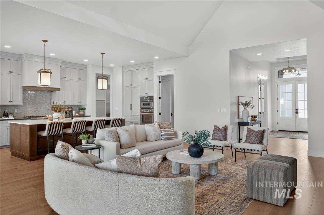 Living area with french doors, light wood-type flooring, recessed lighting, and high vaulted ceiling