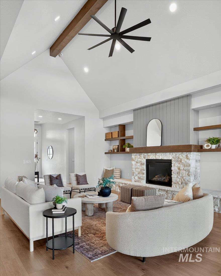 Living room with beam ceiling, recessed lighting, light wood-style floors, high vaulted ceiling, and a stone fireplace