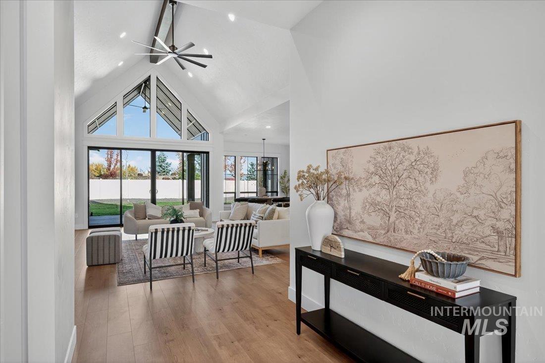 Living area featuring high vaulted ceiling, light wood-style flooring, and a ceiling fan