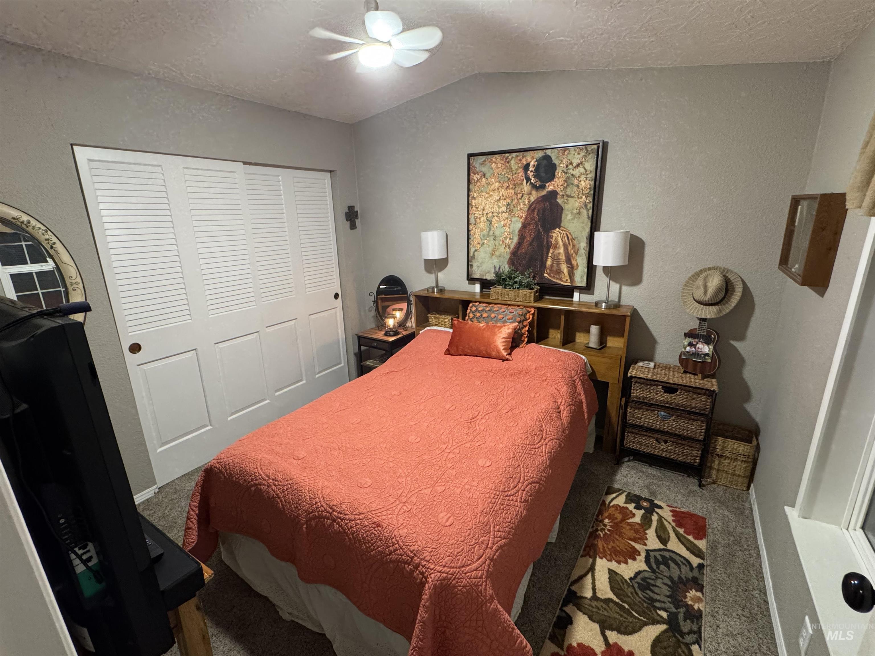 Carpeted bedroom featuring a textured ceiling, a textured wall, a closet, lofted ceiling, and ceiling fan