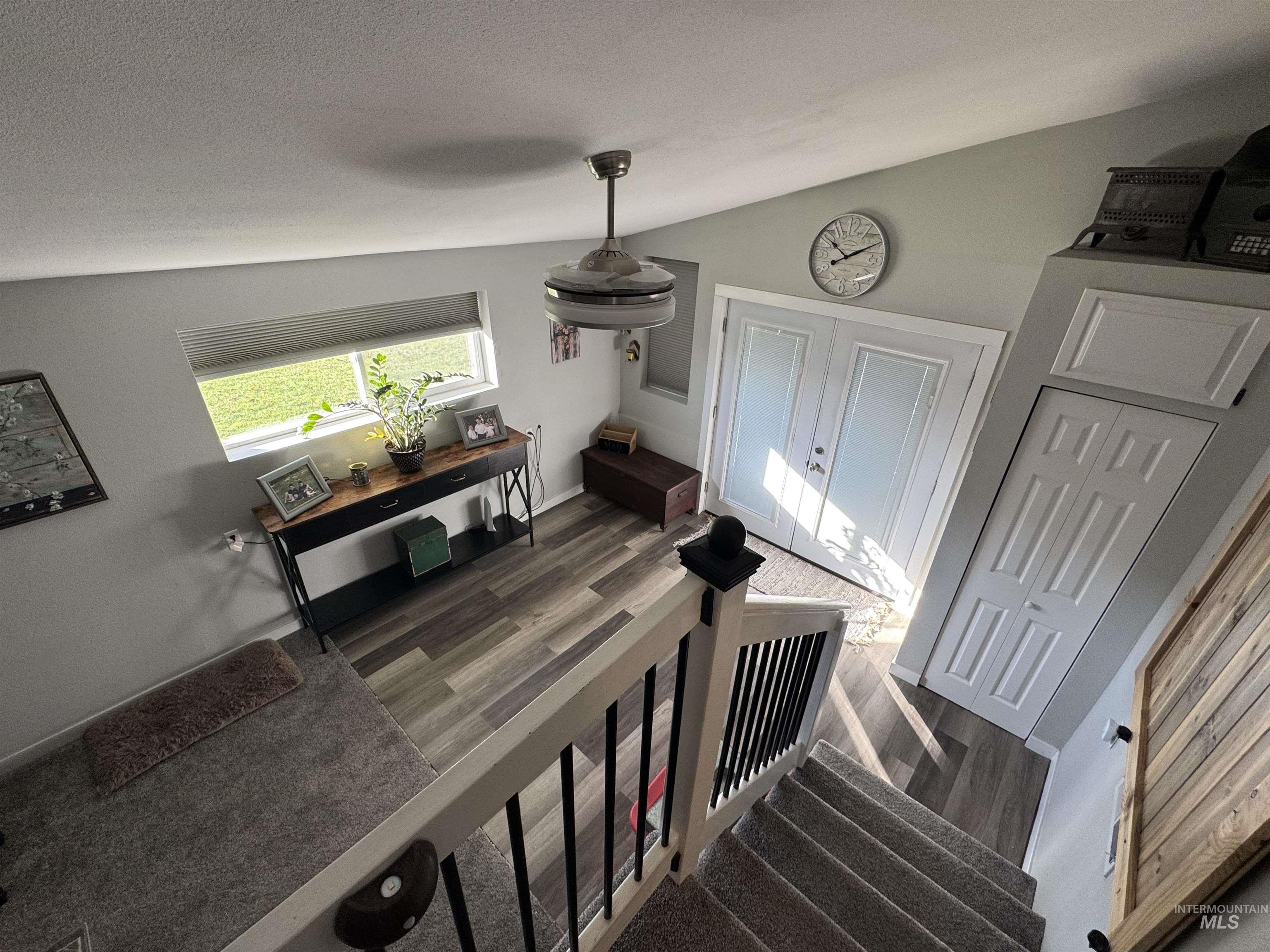 Stairs featuring wood finished floors, a textured ceiling, and vaulted ceiling