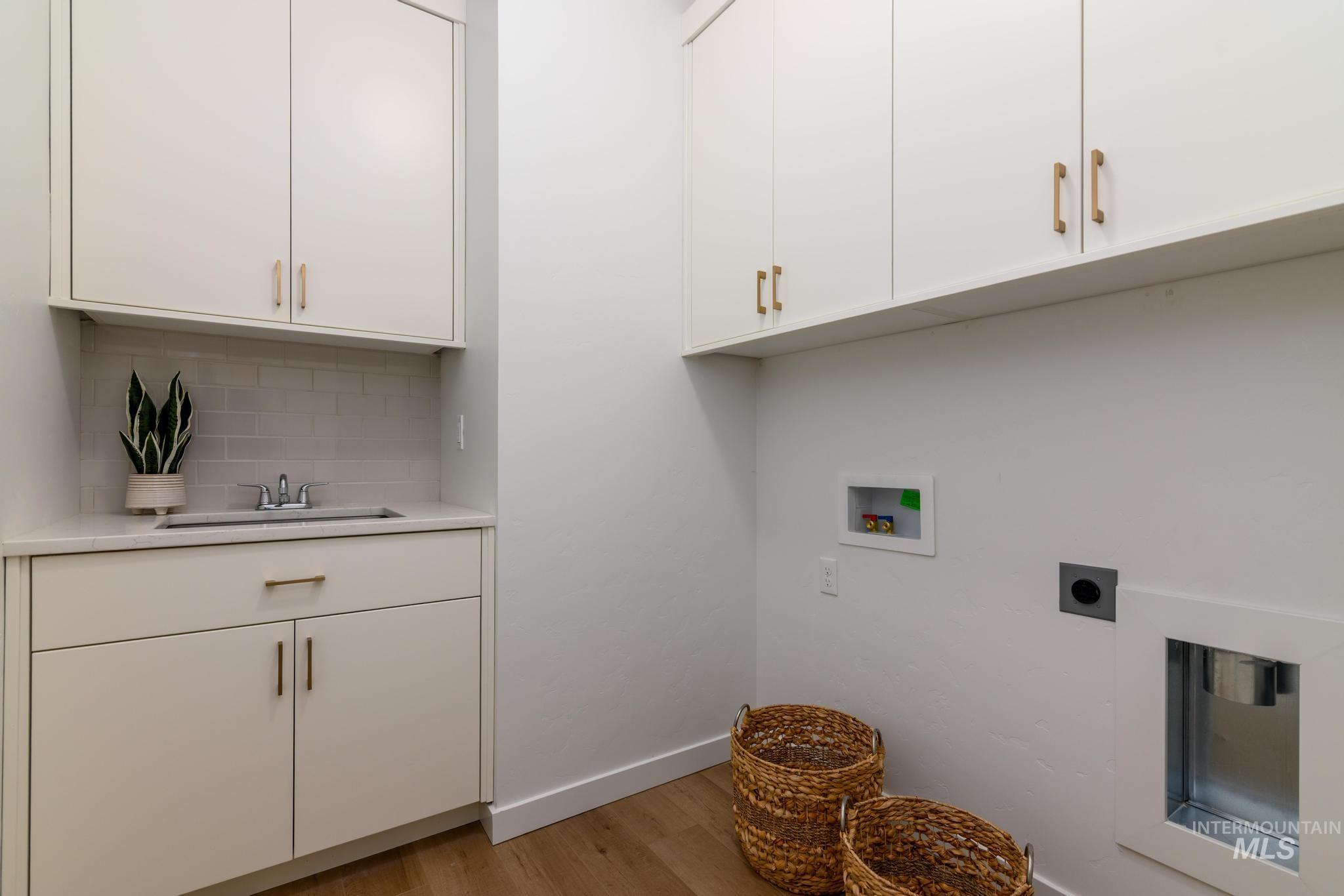 Laundry area featuring light wood-style floors, cabinet space, washer hookup, and electric dryer hookup