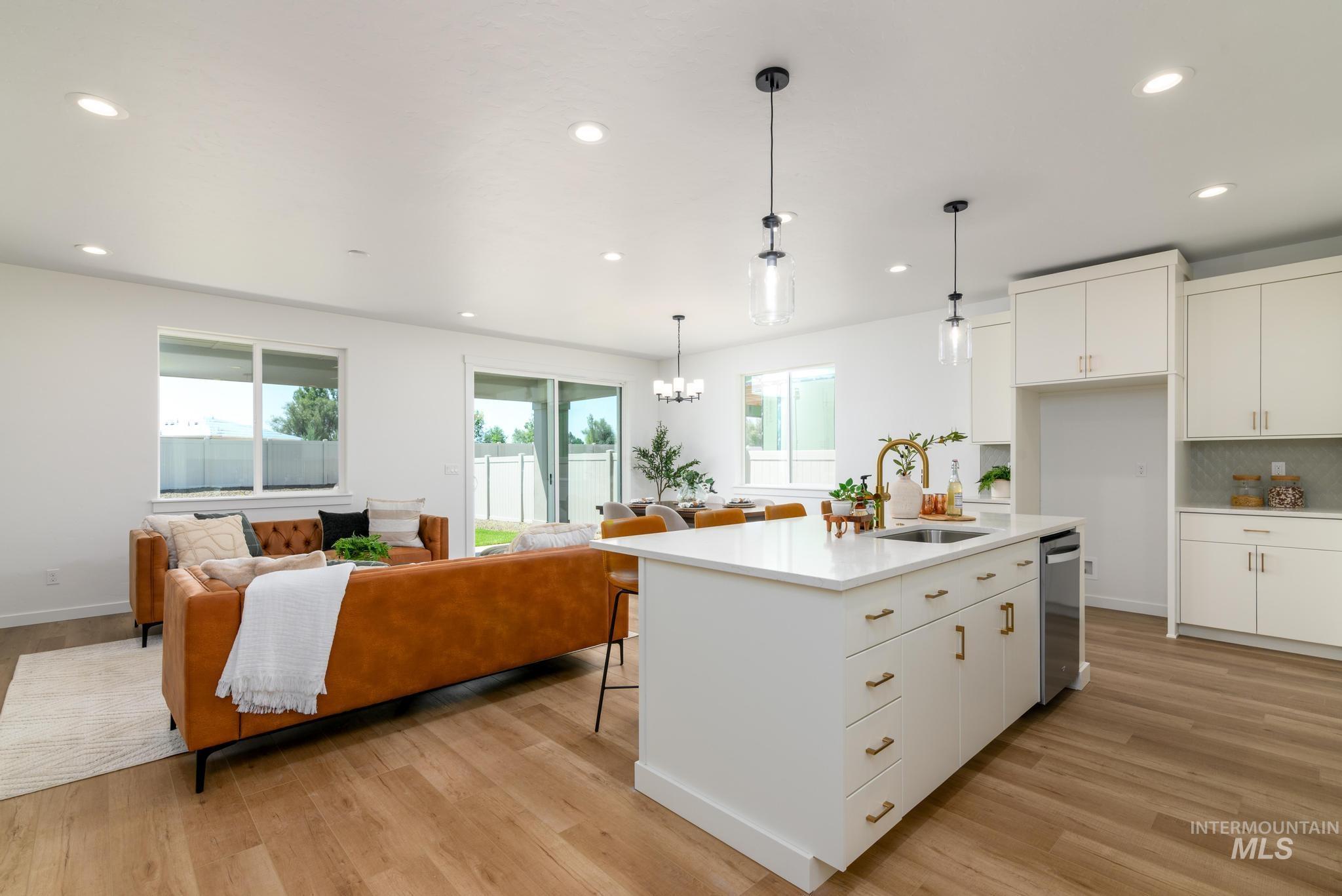 Kitchen with a kitchen bar, white cabinets, open floor plan, hanging light fixtures, and light wood-style flooring