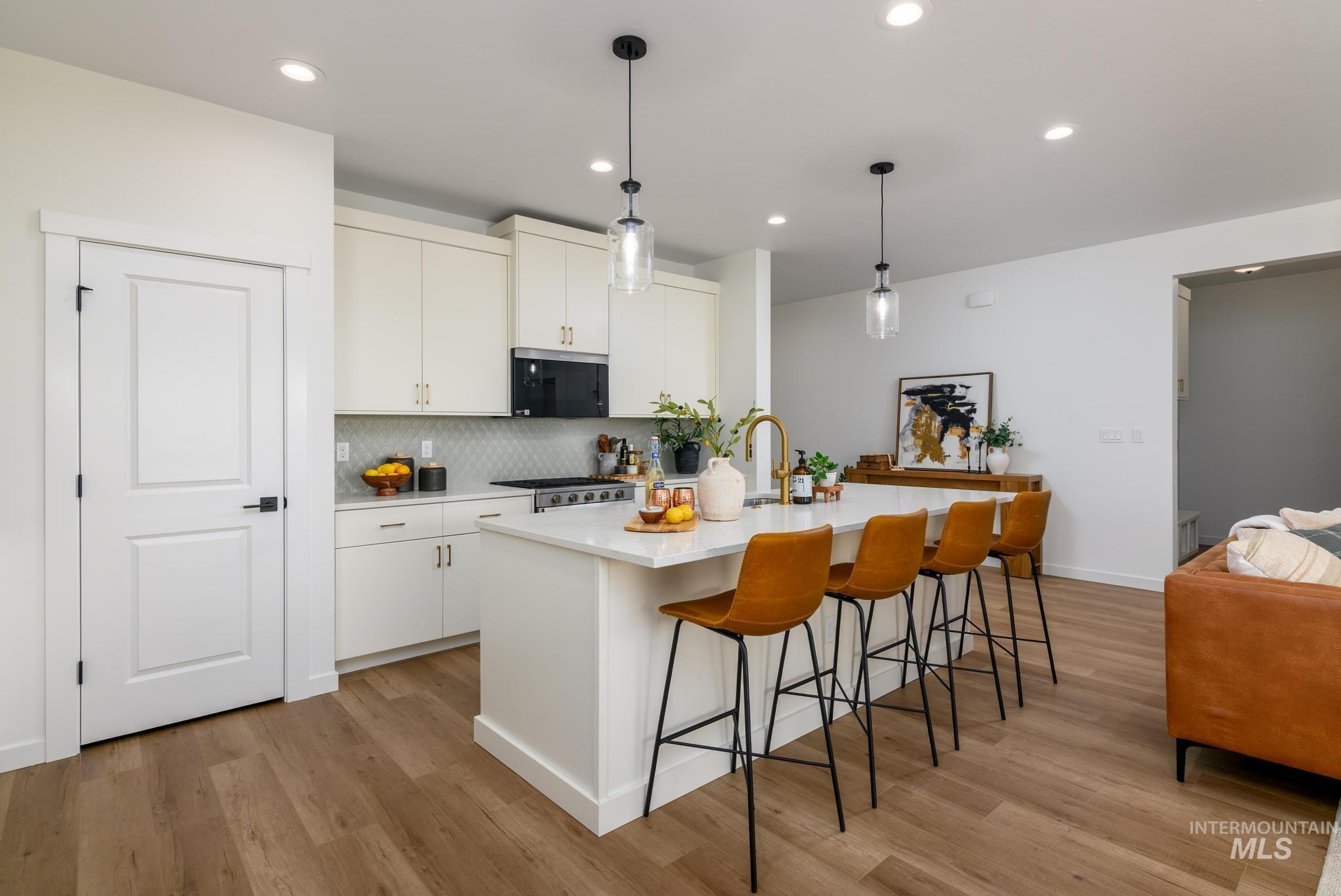 Kitchen with backsplash, a breakfast bar, decorative light fixtures, recessed lighting, and light wood-style flooring