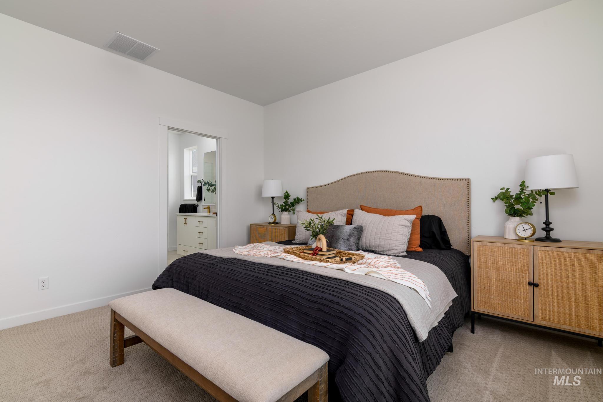 Carpeted bedroom featuring ensuite bath and baseboards