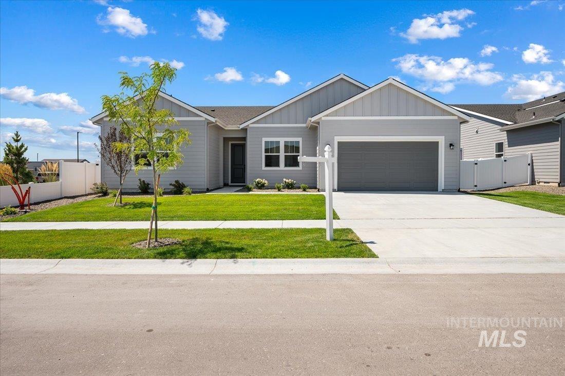 Ranch-style house featuring board and batten siding, driveway, a garage, and a gate