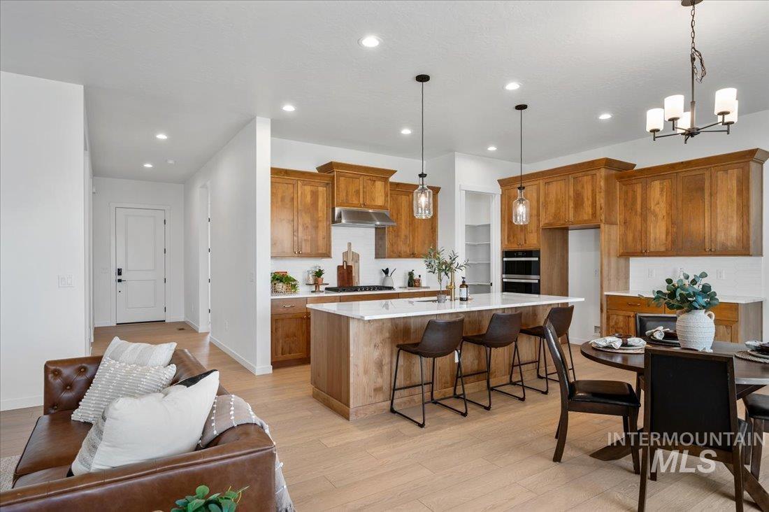 Kitchen with brown cabinets, recessed lighting, tasteful backsplash, and light wood finished floors
