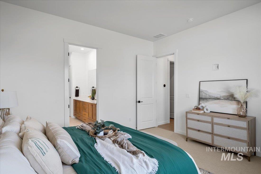 Bedroom featuring light carpet and ensuite bathroom