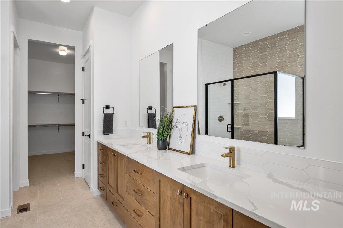 Bathroom featuring double vanity, a stall shower, recessed lighting, and a spacious closet