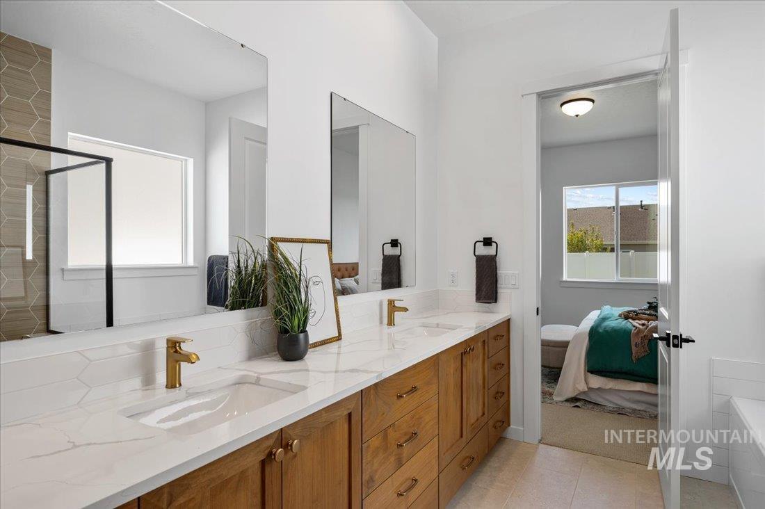 Bathroom with ensuite bathroom, double vanity, a tub, and a shower