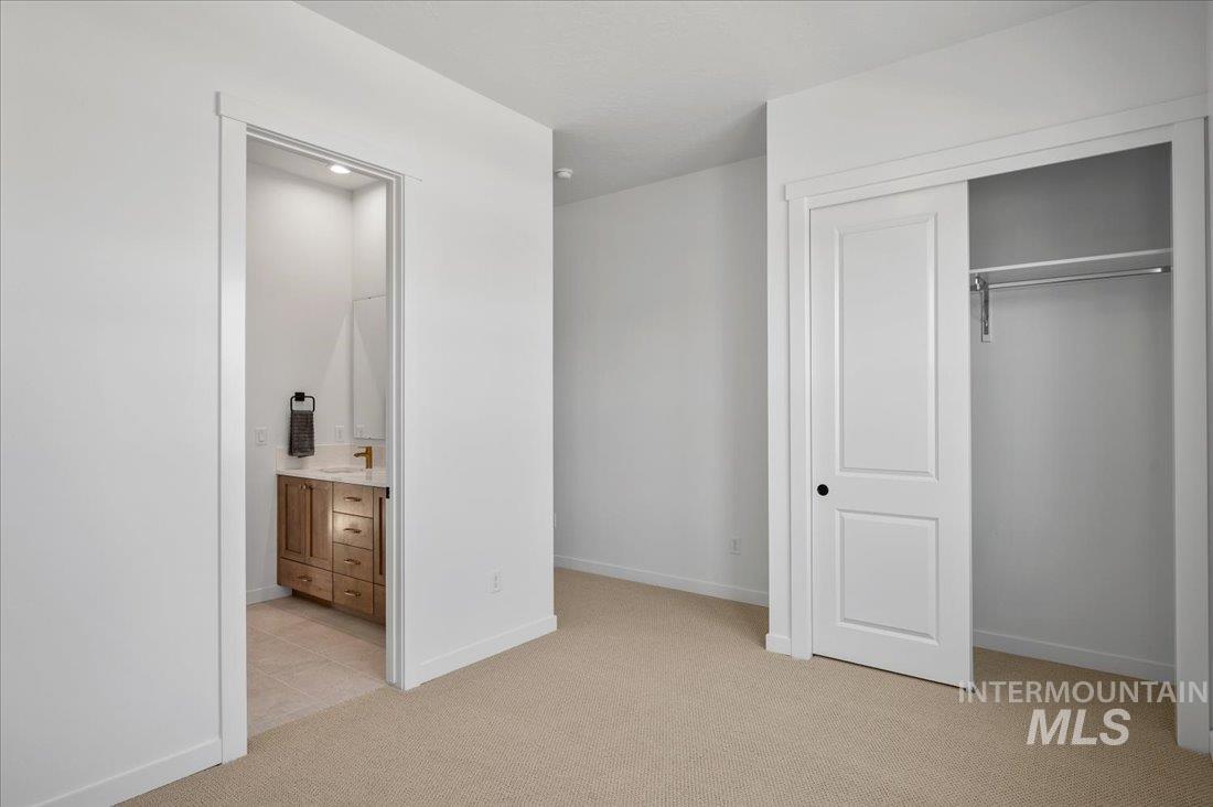 Unfurnished bedroom with light carpet, a closet, and connected bathroom