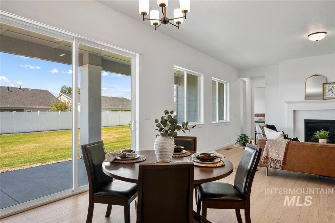 Dining room with light wood-style flooring, a chandelier, and a fireplace