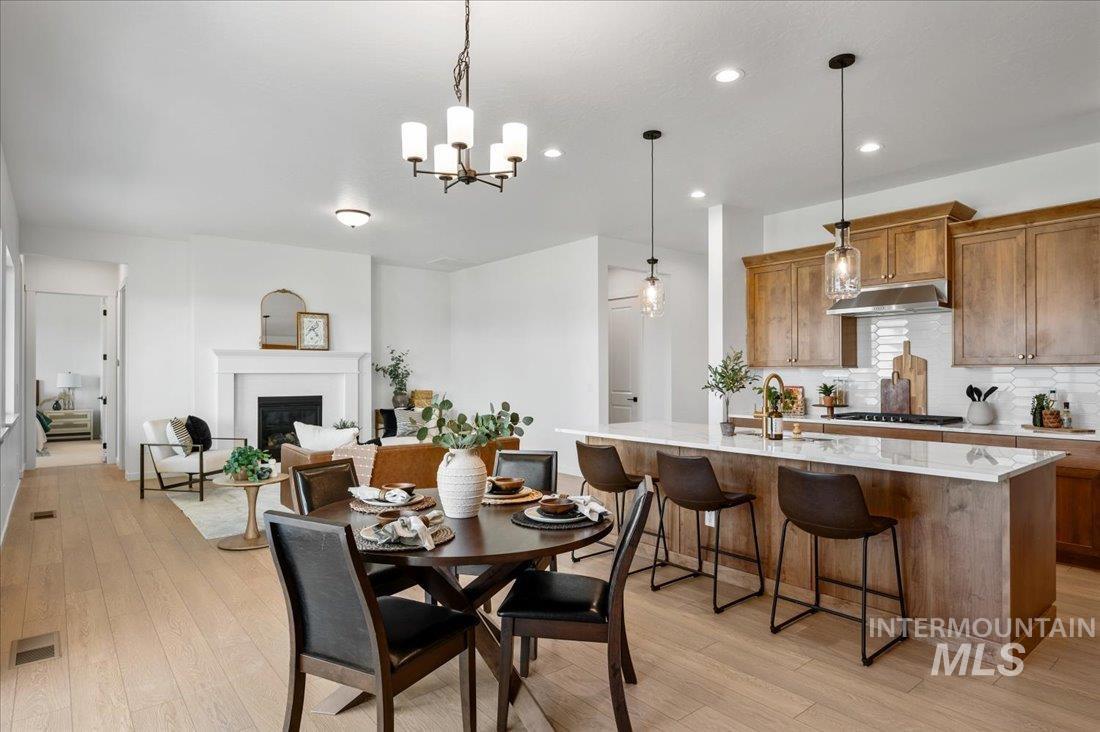 Dining room with light wood-style flooring, a glass covered fireplace, a chandelier, and recessed lighting