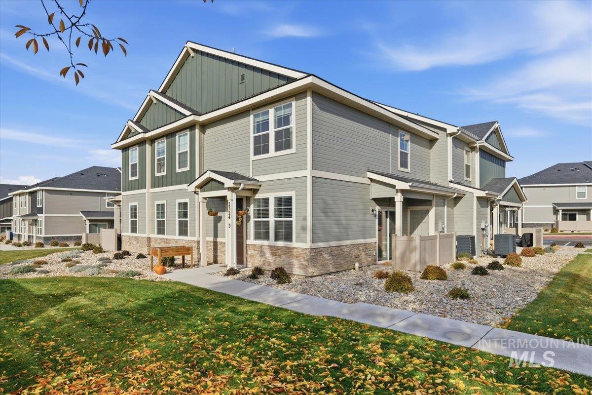 Craftsman-style home with board and batten siding, stone siding, a front lawn, and a residential view