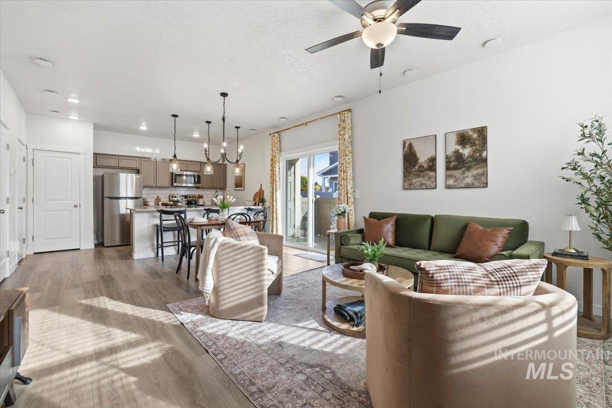 Living room featuring light wood-style floors, a textured ceiling, a ceiling fan, and recessed lighting