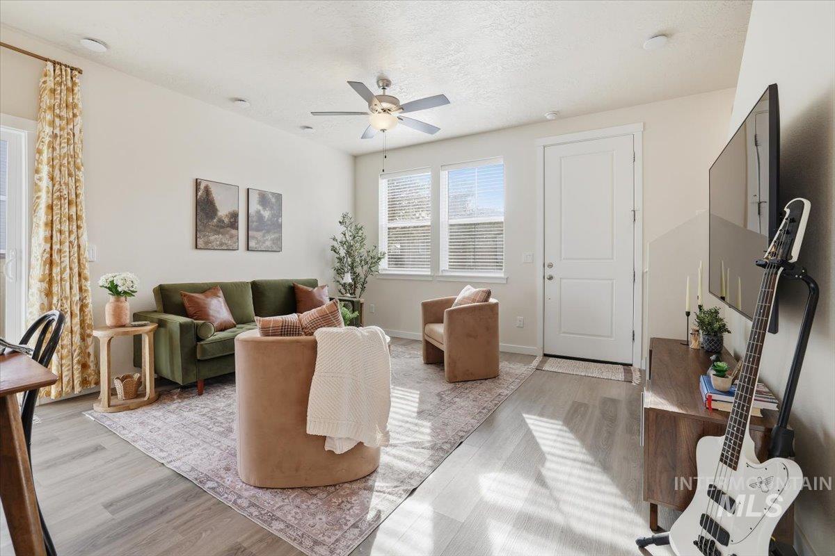 Living room with wood finished floors, a ceiling fan, and a textured ceiling