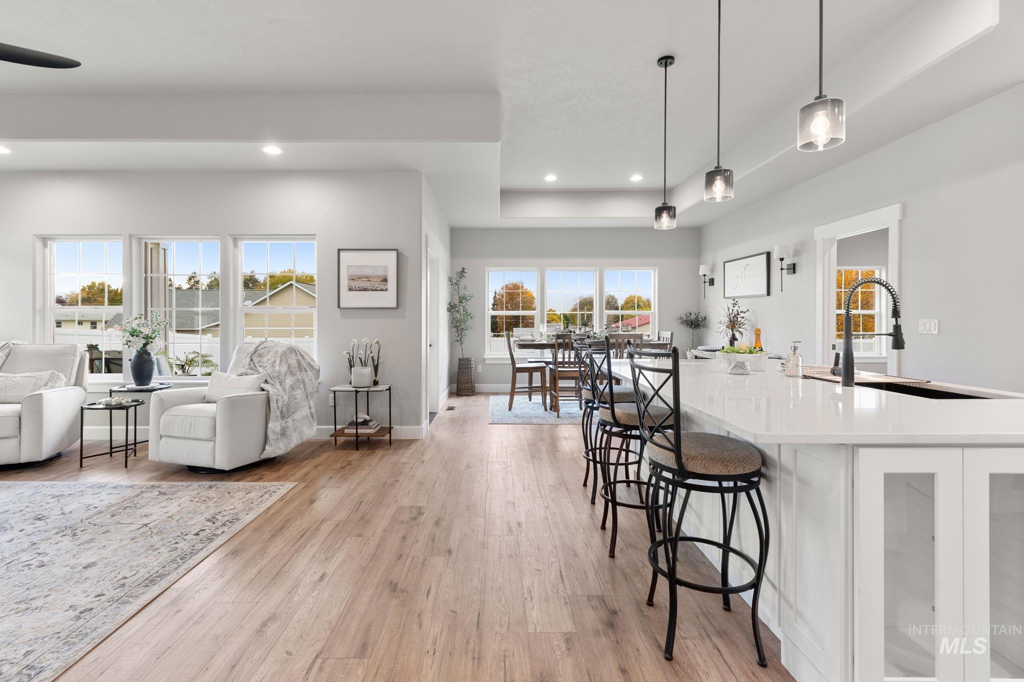Kitchen with a raised ceiling, pendant lighting, a kitchen bar, light wood-type flooring, and open floor plan