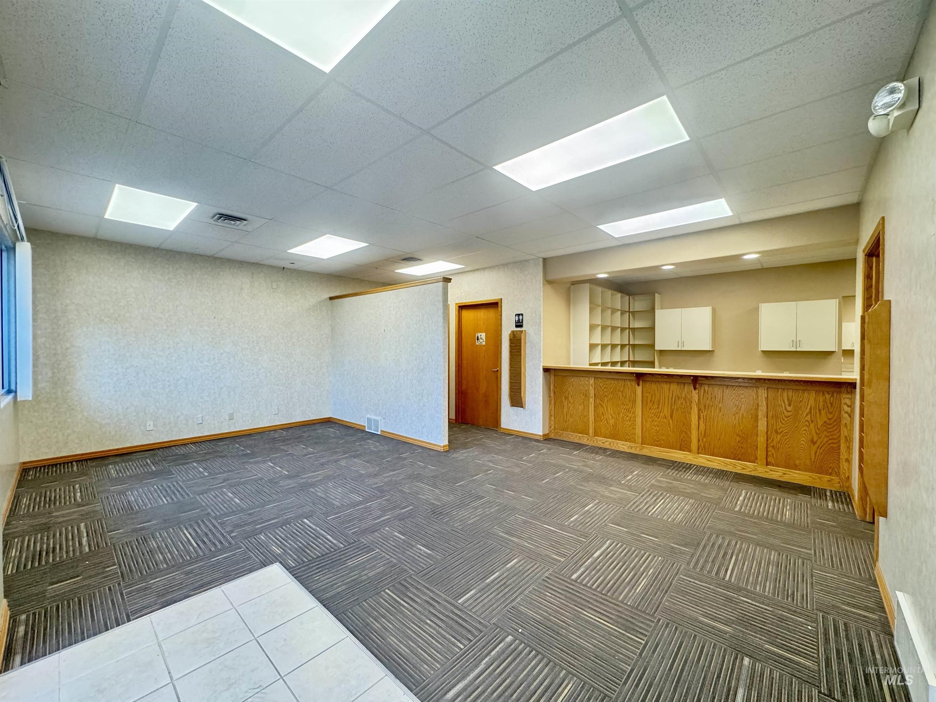 Carpeted spare room featuring a paneled ceiling and tile patterned floors