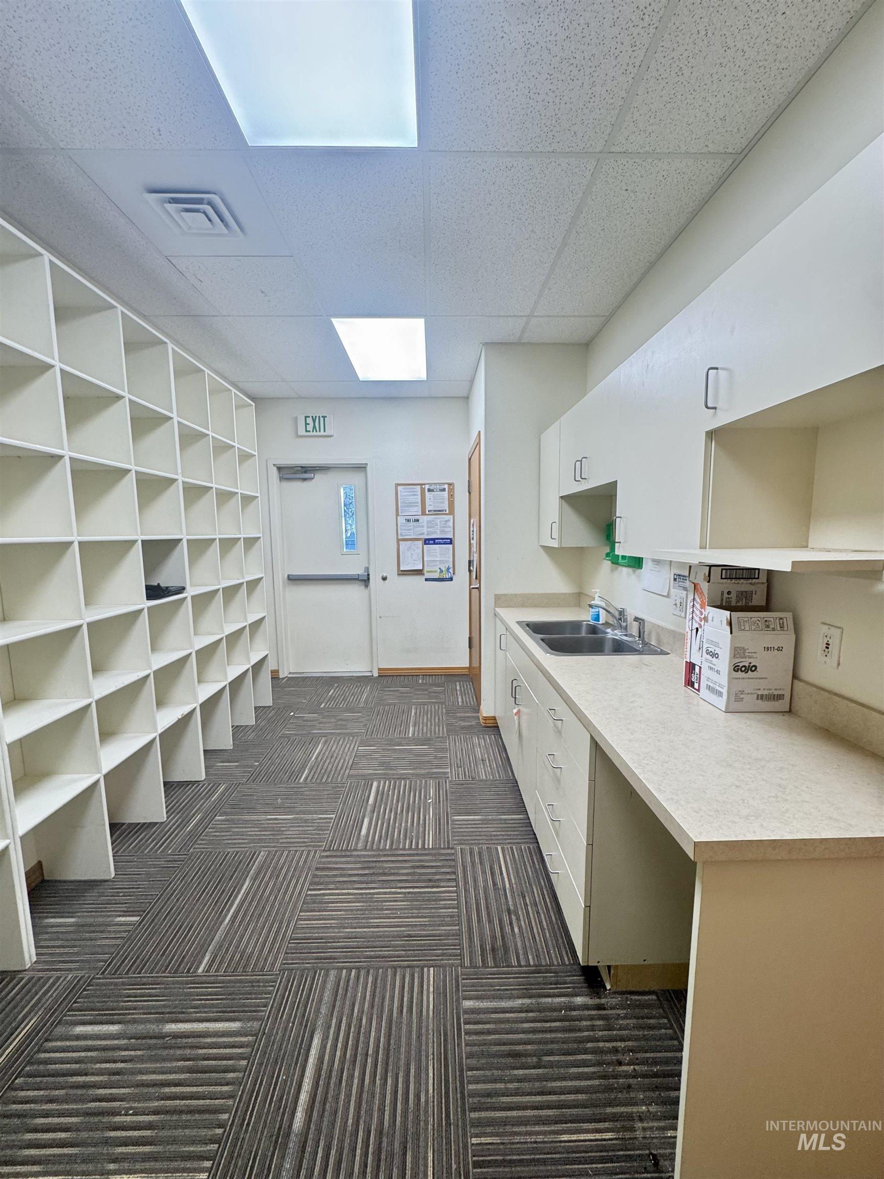 Kitchen with light countertops, open shelves, white cabinetry, and a paneled ceiling