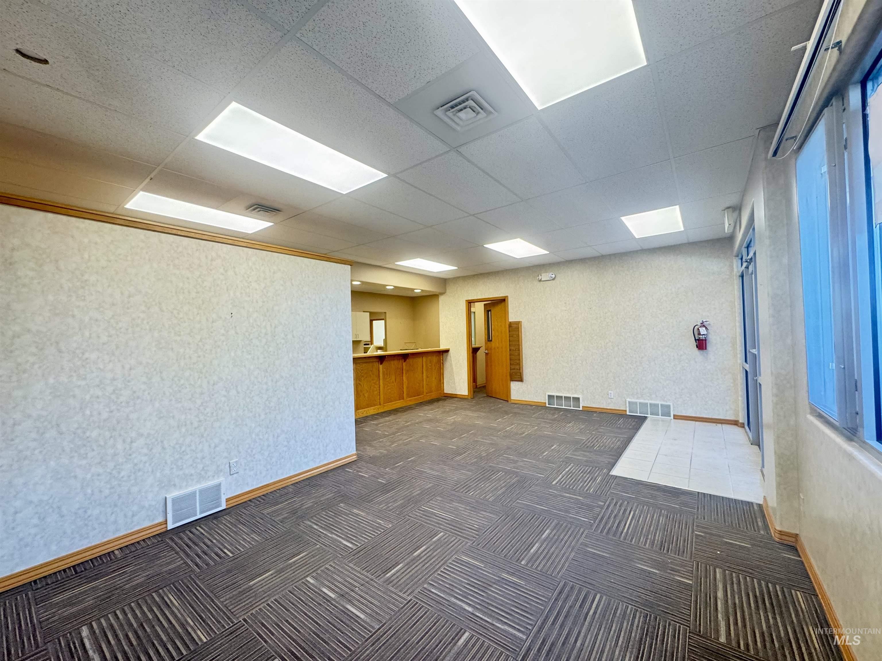 Carpeted spare room with wallpapered walls and a paneled ceiling