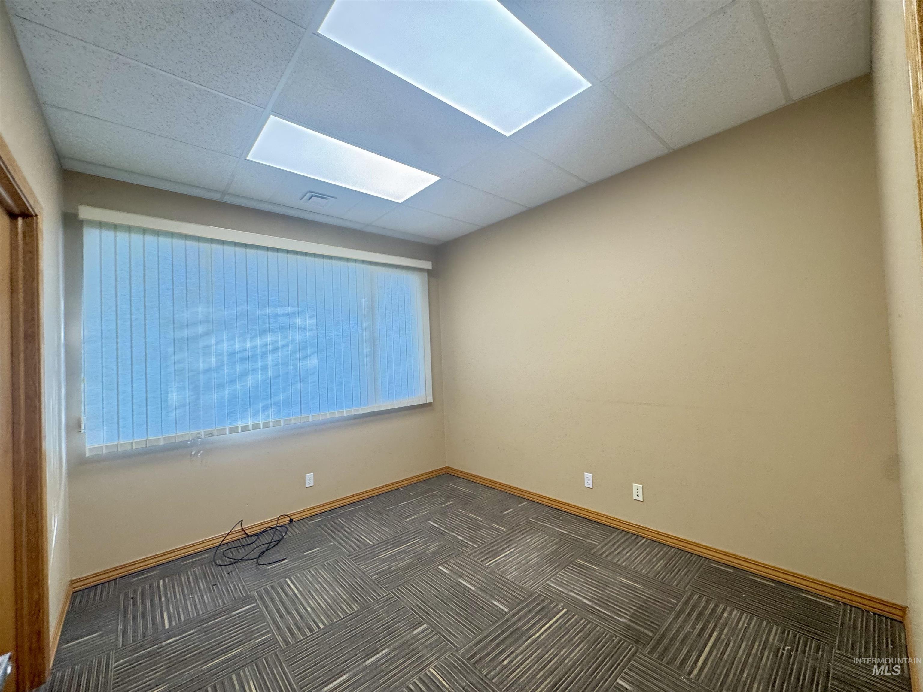 Empty room with a drop ceiling and carpet floors