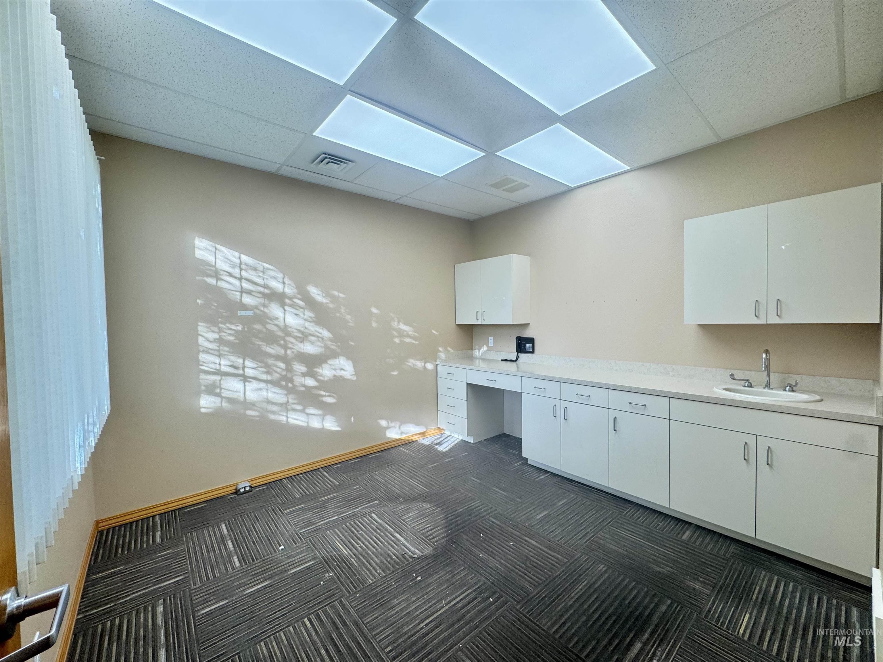 Unfurnished office with a paneled ceiling and built in desk