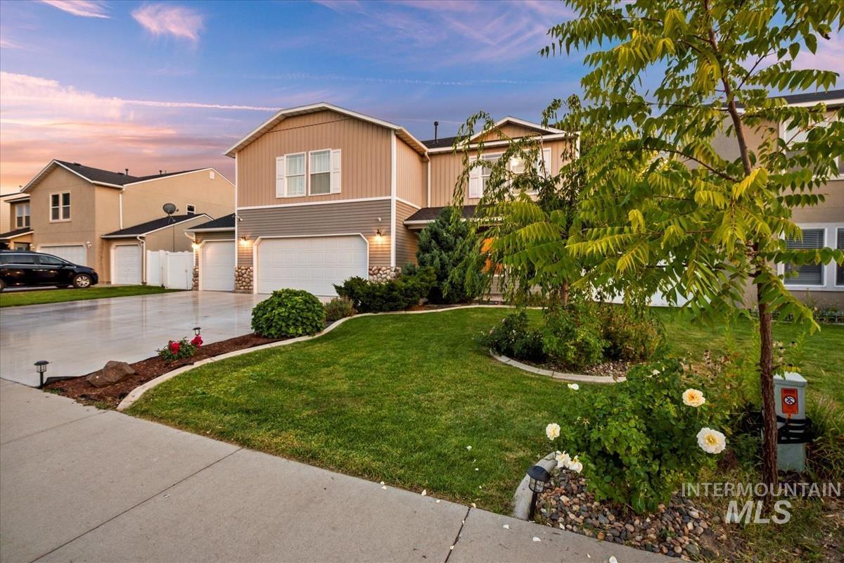 View of front facade featuring concrete driveway, an attached garage, and a lawn
