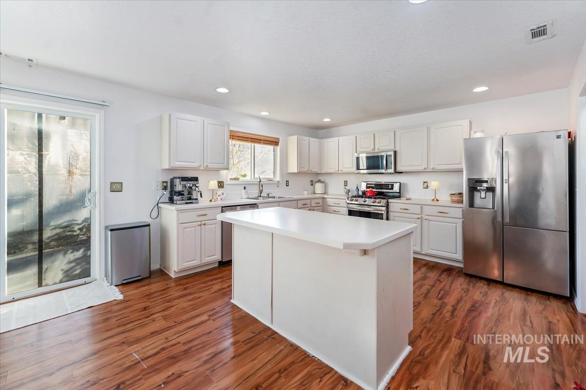 Kitchen featuring stainless steel appliances, white cabinets, light countertops, and recessed lighting