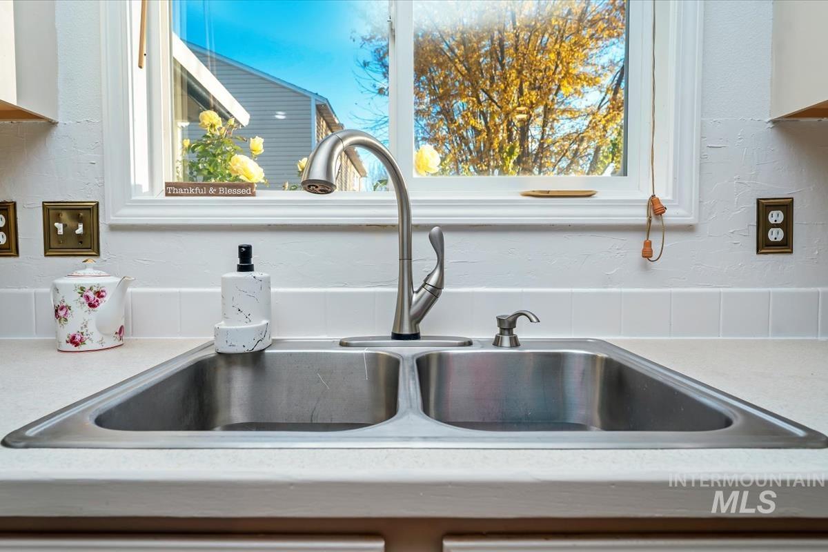 Kitchen view of a textured wall, light countertops, and white cabinets