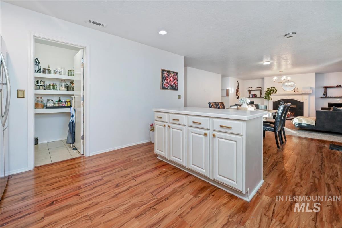 Kitchen featuring light countertops, light wood-type flooring, open floor plan, white cabinets, and a chandelier