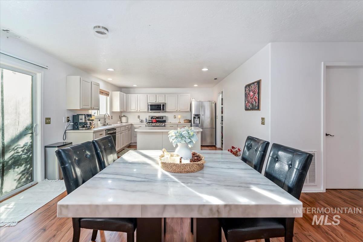 Dining room with dark wood-style flooring and recessed lighting