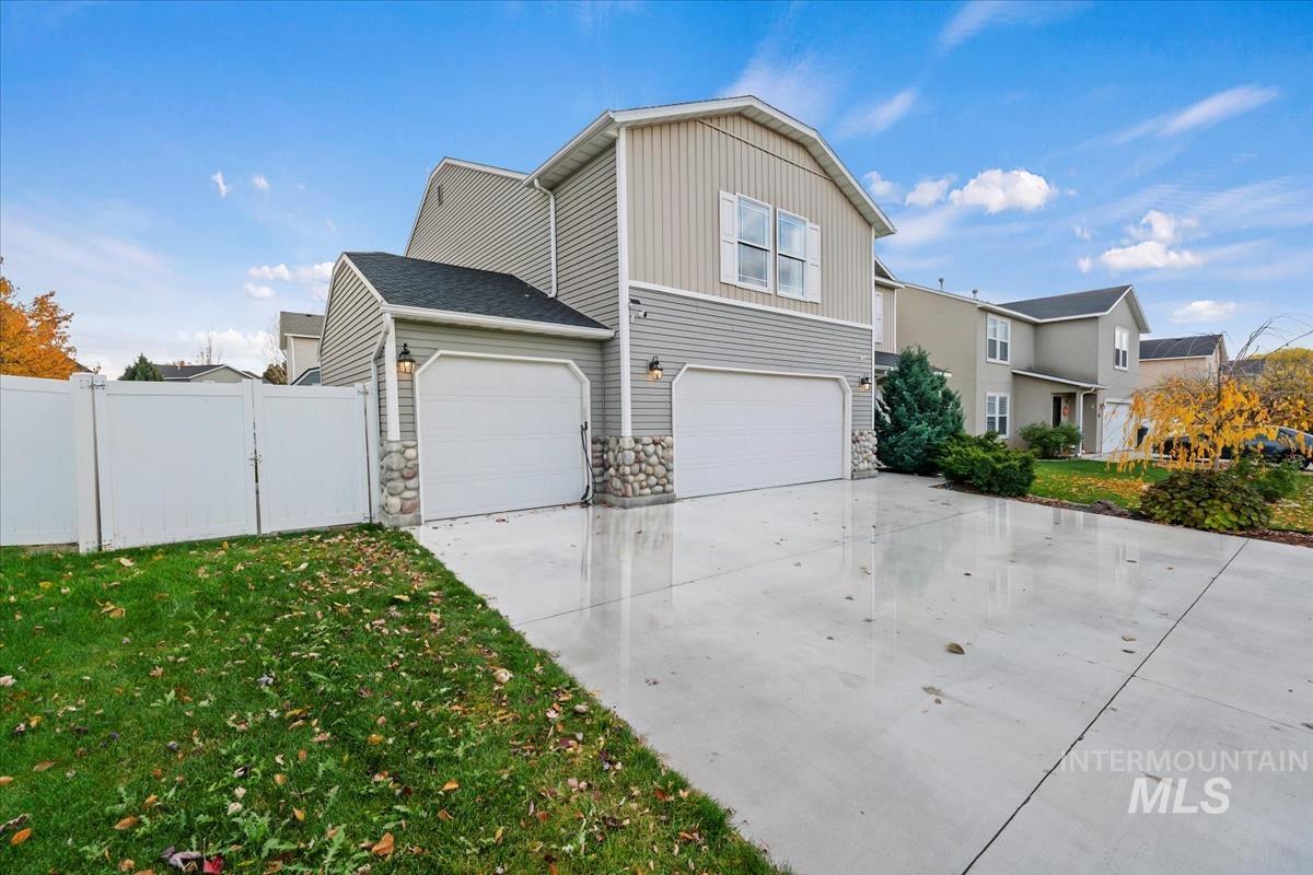 View of home's exterior with driveway, stone siding, and a garage