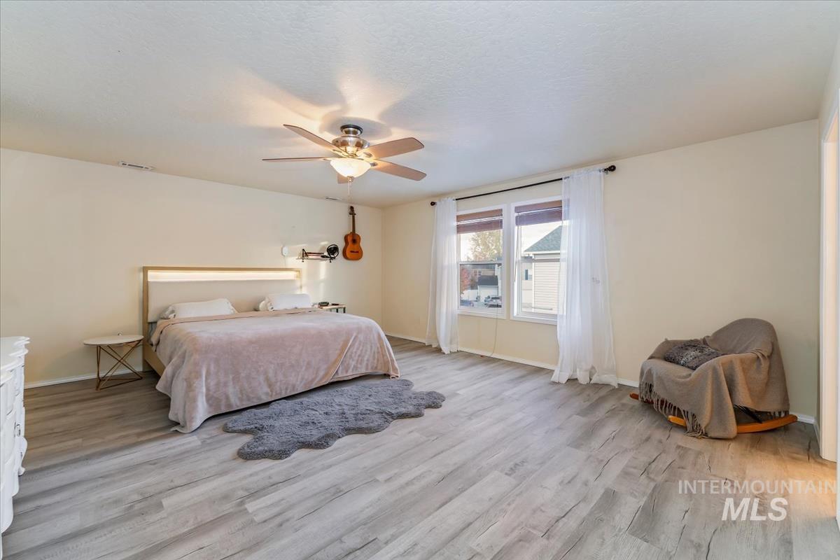 Bedroom featuring light wood finished floors, a ceiling fan, and a textured ceiling
