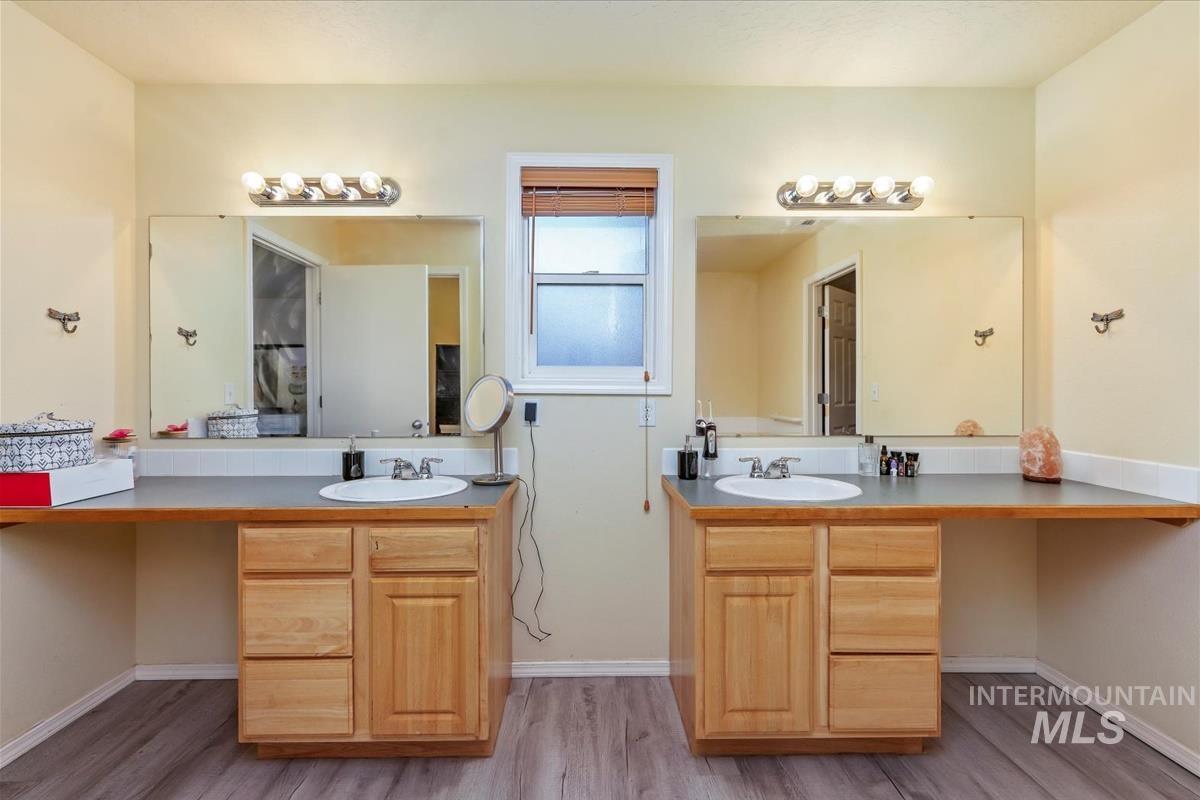 Full bathroom with light wood-style flooring and two vanities