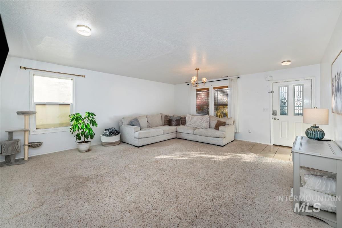 Carpeted living room with a chandelier and a textured ceiling