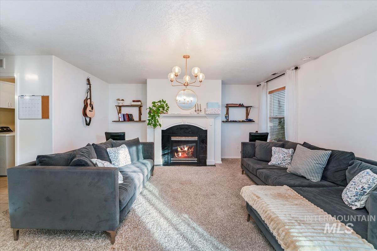 Carpeted living area with a fireplace, washer / dryer, and a chandelier