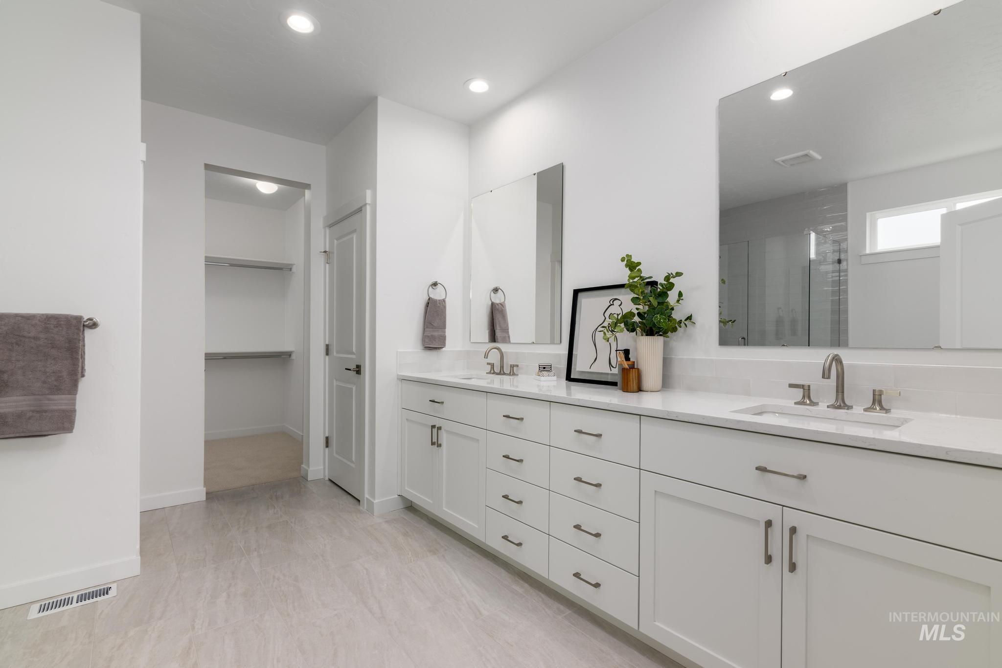 Full bath featuring double vanity, recessed lighting, a walk in closet, and a shower stall