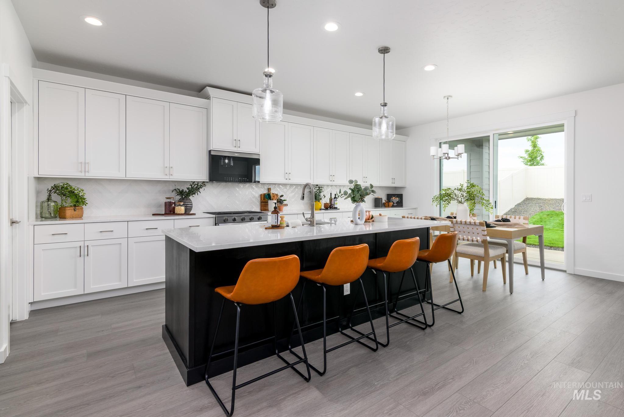 Kitchen with white cabinets, dark cabinetry, tasteful backsplash, hanging light fixtures, and recessed lighting