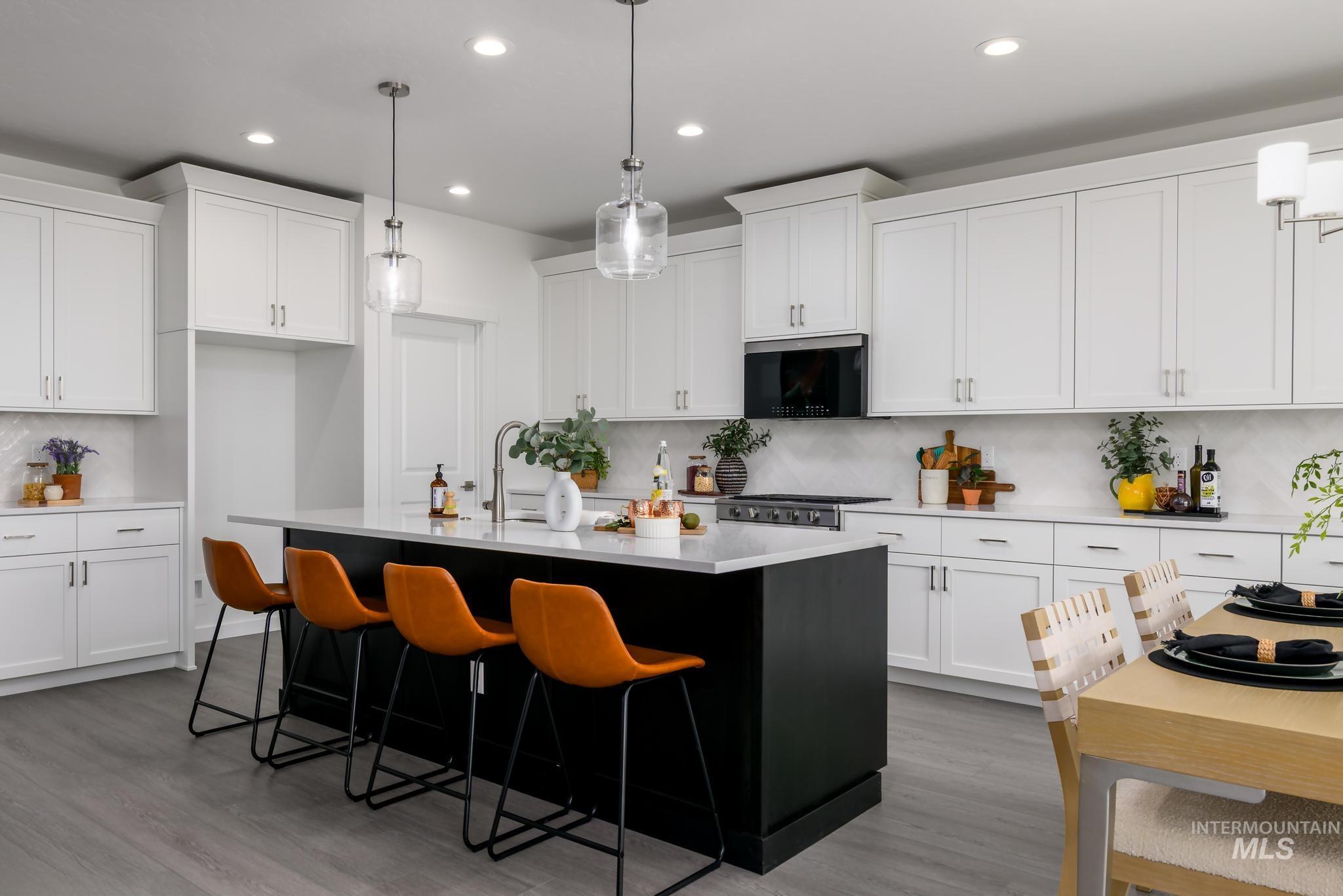 Kitchen with tasteful backsplash, a center island with sink, pendant lighting, light wood finished floors, and recessed lighting