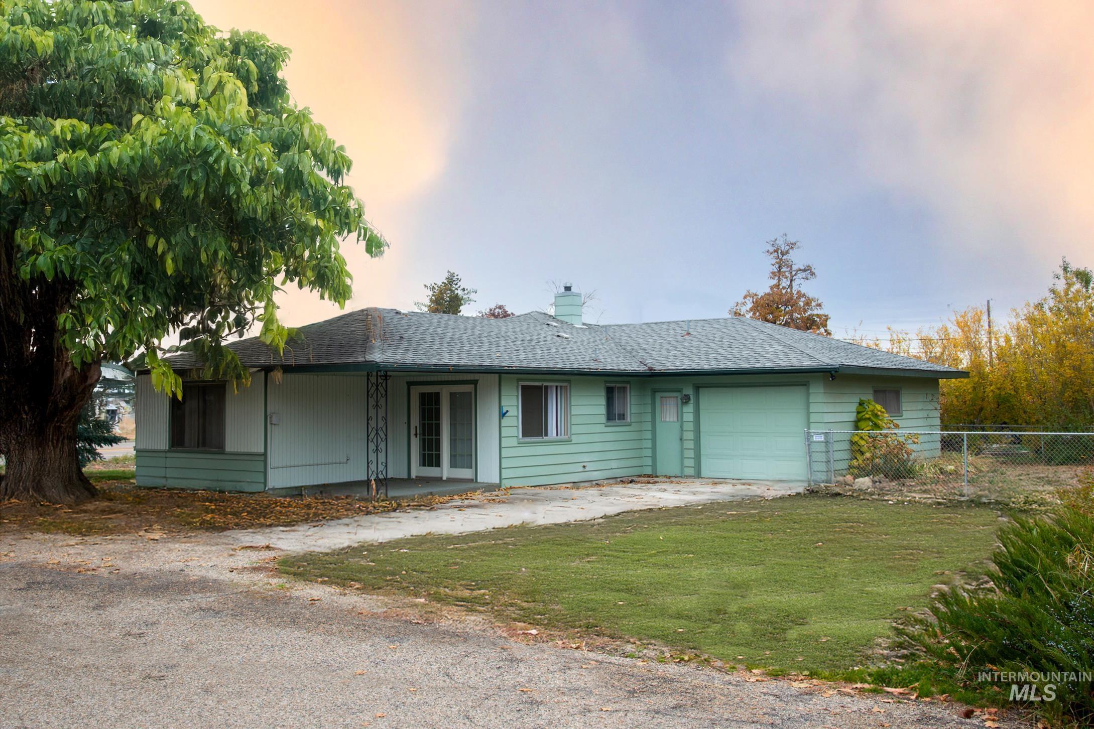 Ranch-style home with an attached garage, driveway, a patio area, roof with shingles, and a chimney