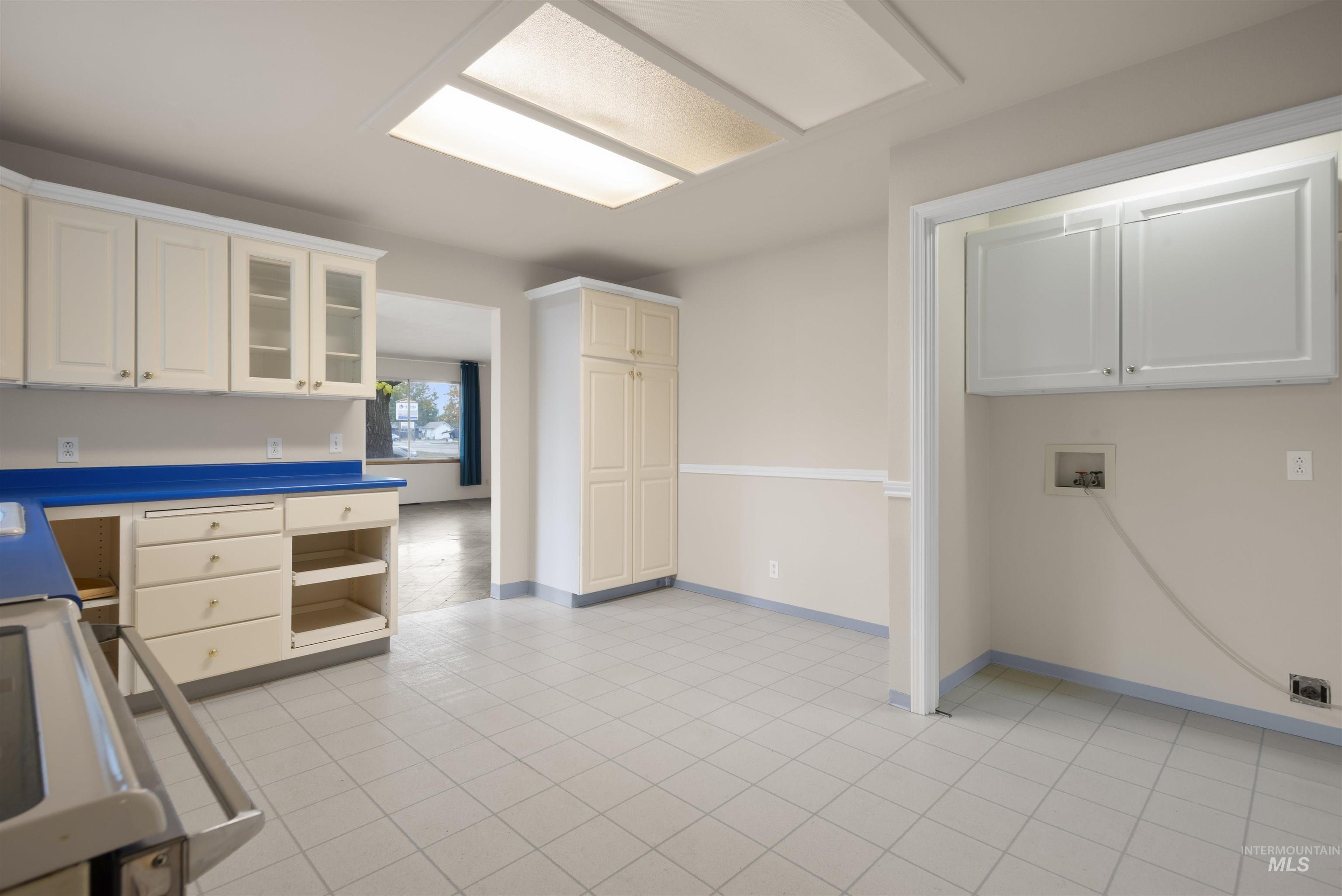Washroom with washer hookup, light tile patterned floors, an office area, and cabinet space
