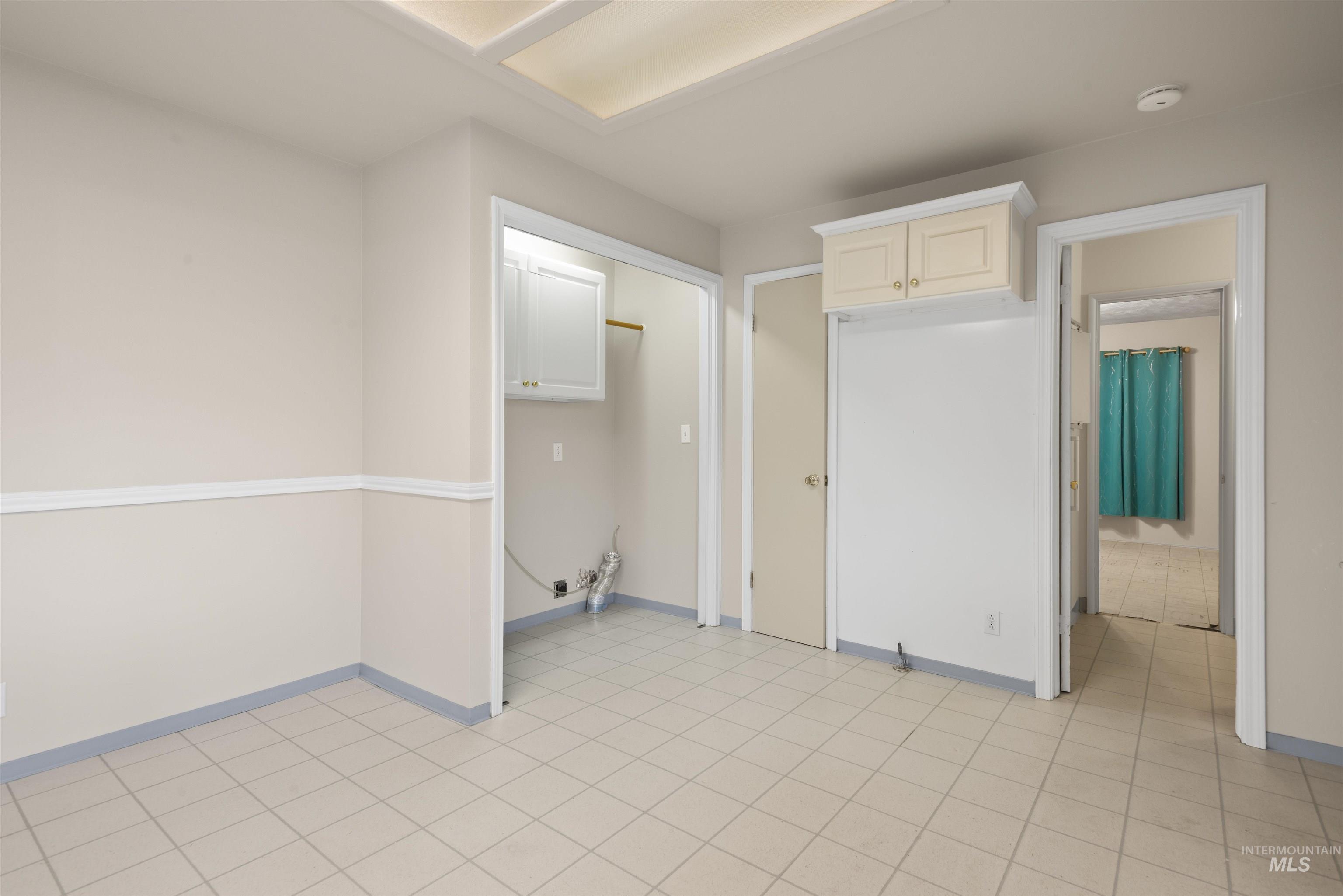 Empty room with light tile patterned floors and baseboards