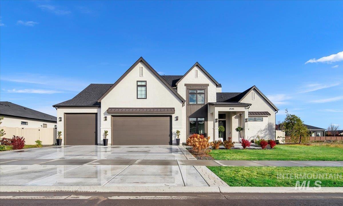 Modern inspired farmhouse with a standing seam roof, a metal roof, driveway, and stucco siding