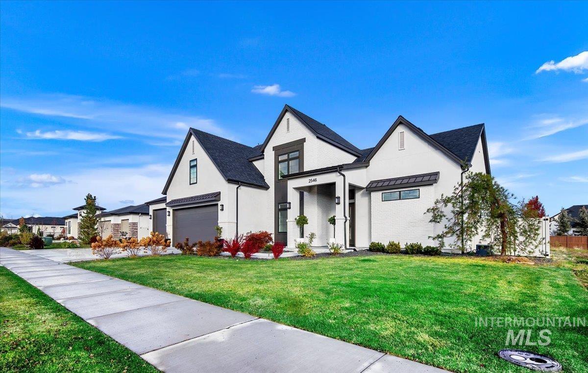 Modern inspired farmhouse with a front lawn, a garage, a standing seam roof, a metal roof, and stucco siding