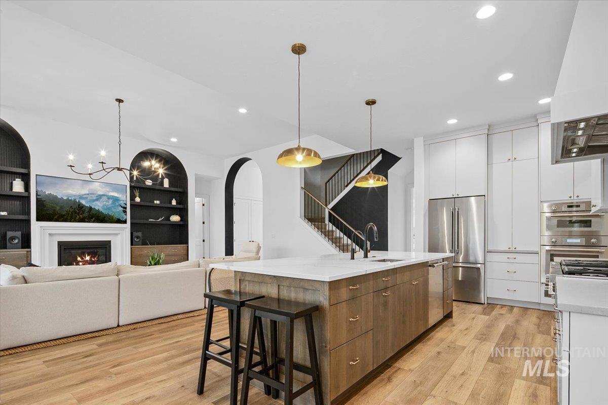 Kitchen featuring a glass covered fireplace, a breakfast bar area, a chandelier, modern cabinets, and open floor plan