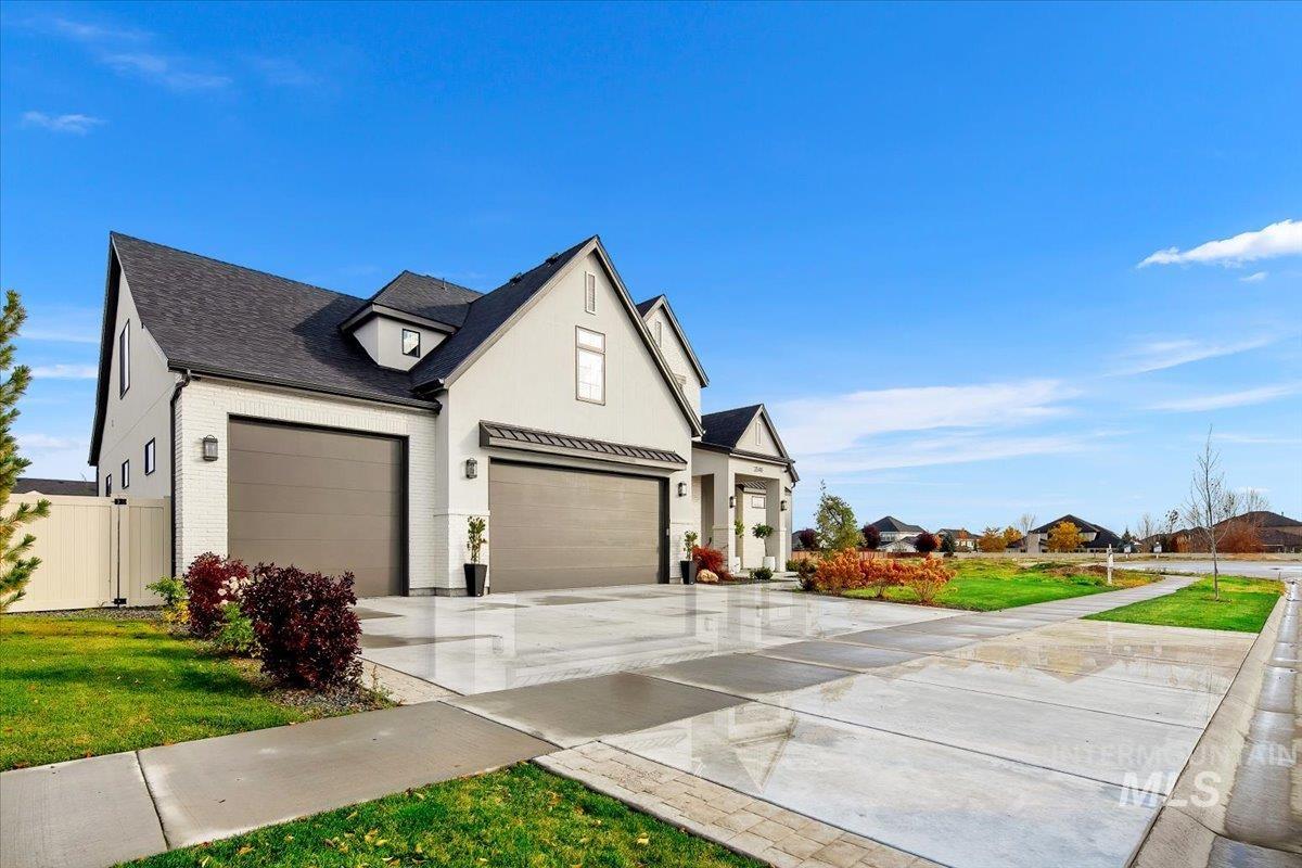 View of side of property featuring brick siding, concrete driveway, roof with shingles, and stucco siding
