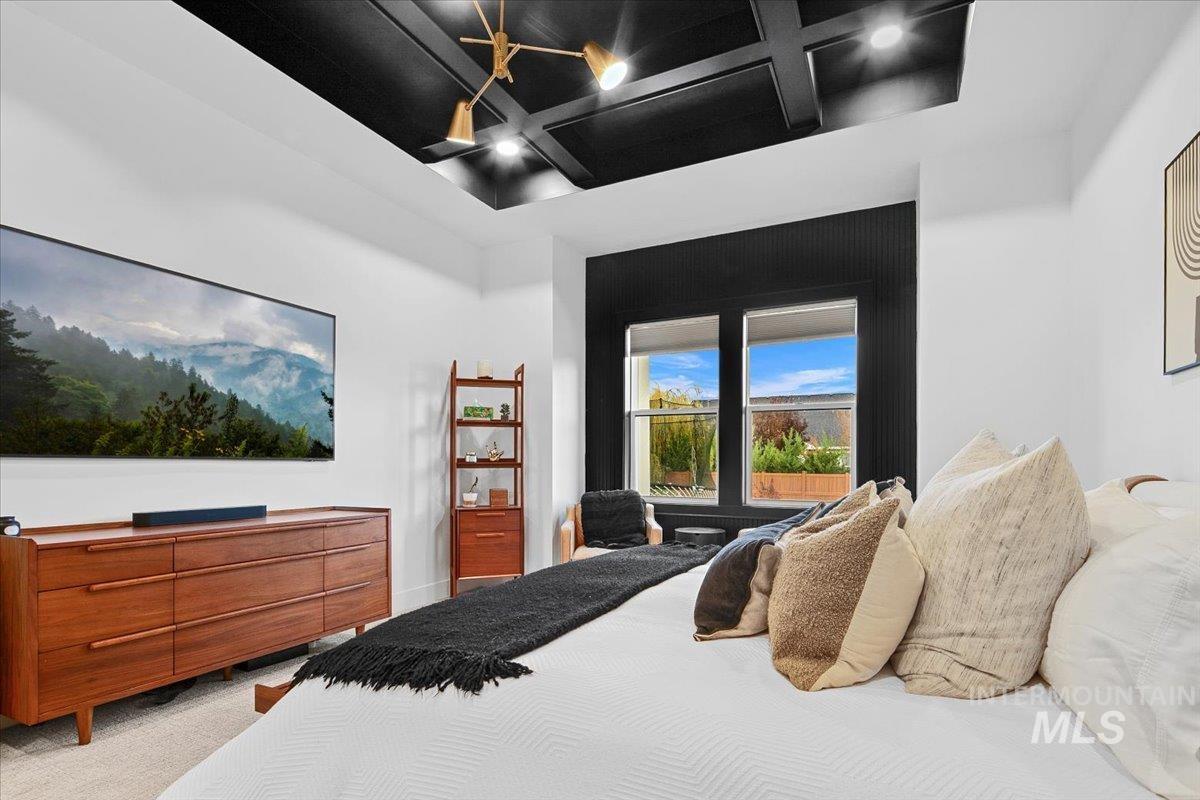 Carpeted bedroom with coffered ceiling and beamed ceiling