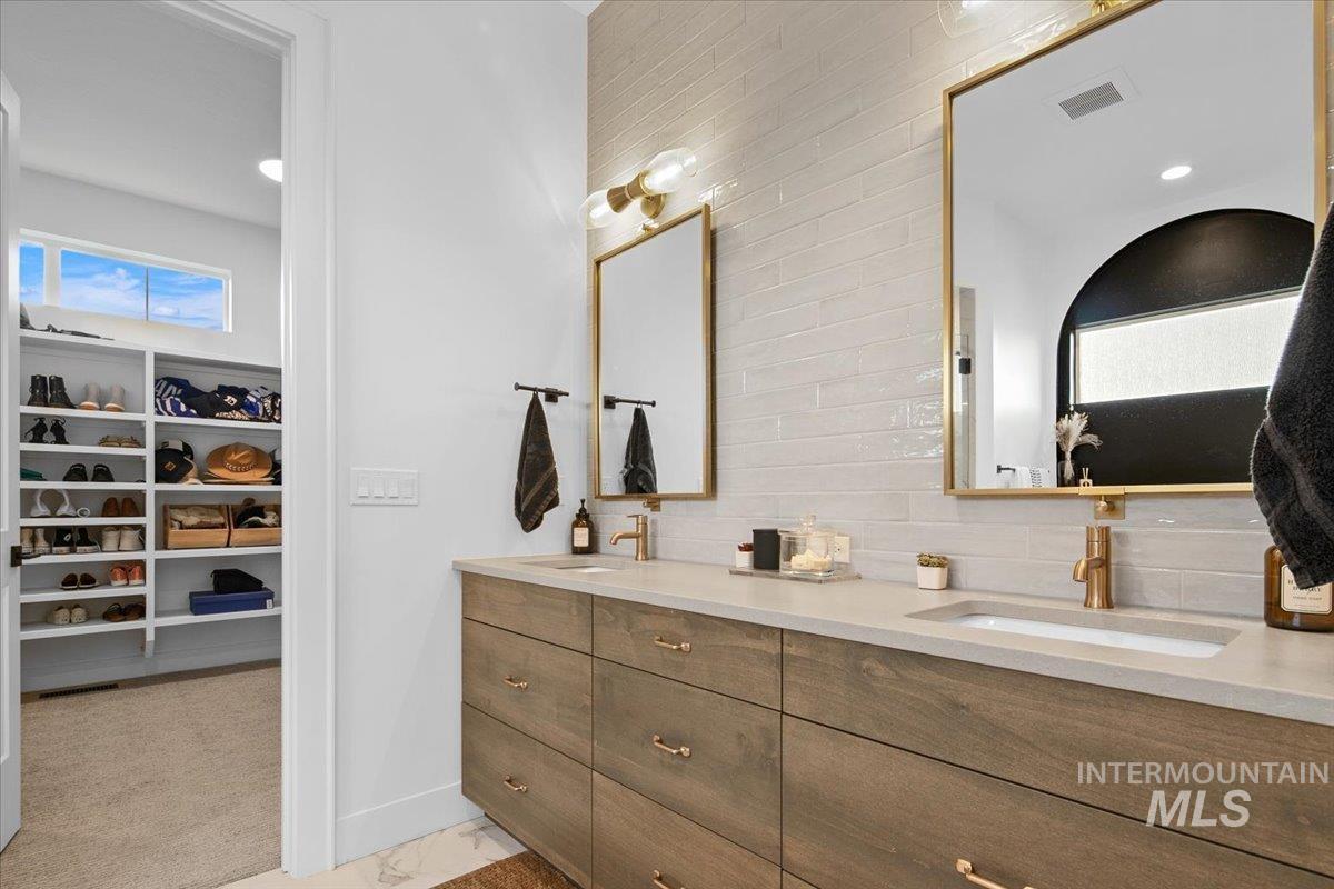 Full bath featuring a walk in closet, double vanity, decorative backsplash, and light colored carpet