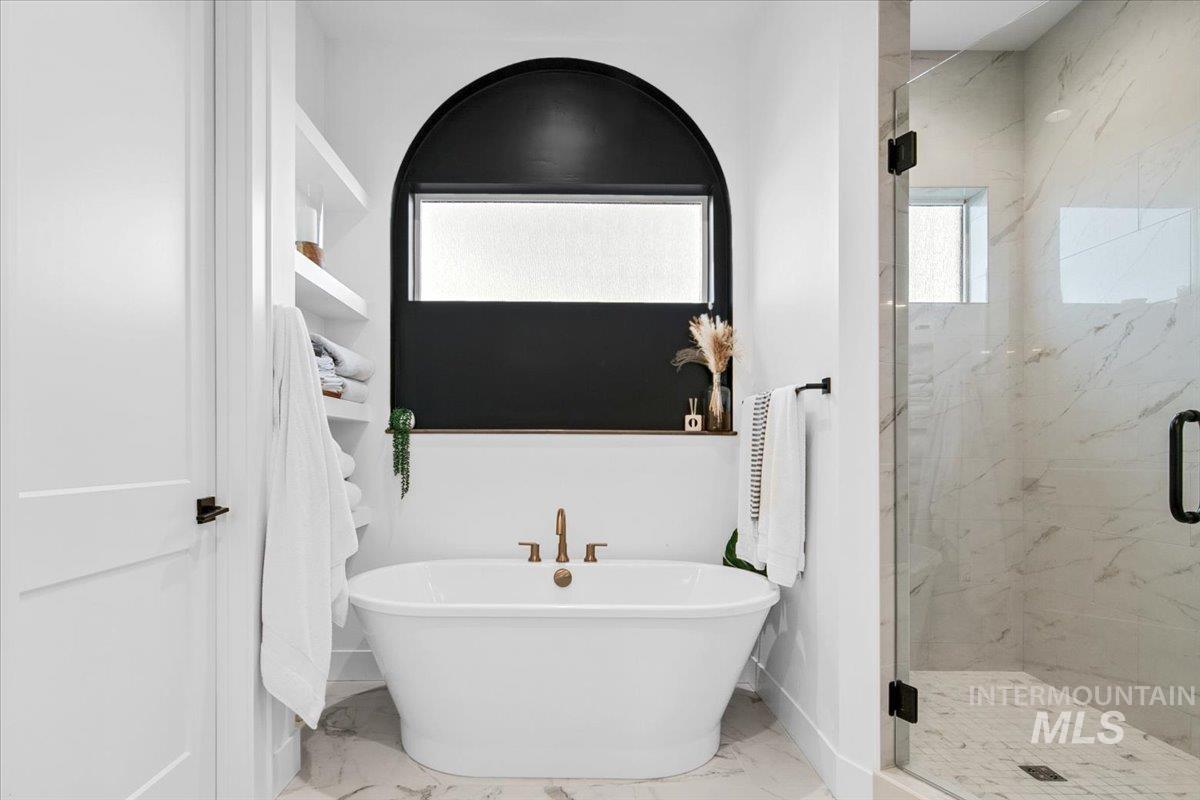 Full bath featuring a marble finish shower, a soaking tub, and marble finish floors