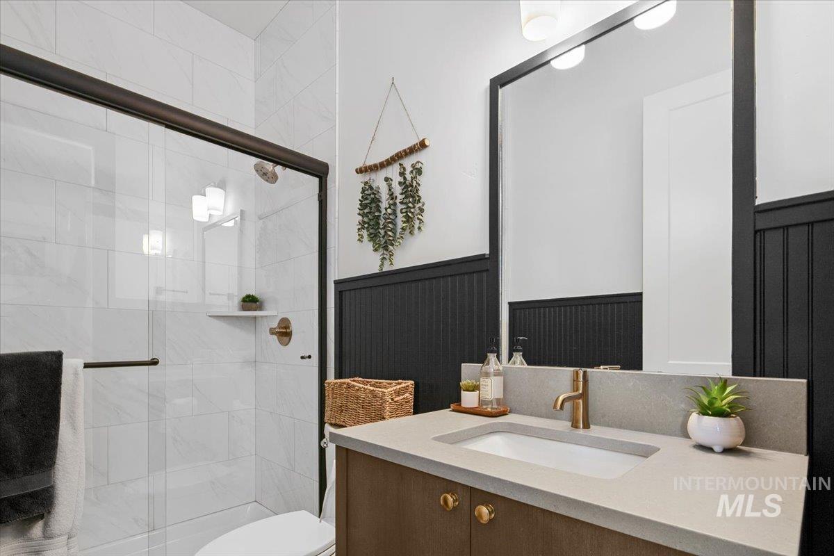 Full bathroom with vanity, a stall shower, and a wainscoted wall